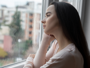 Auszeit Insel Foto Frau schaut traurig aus Fenster